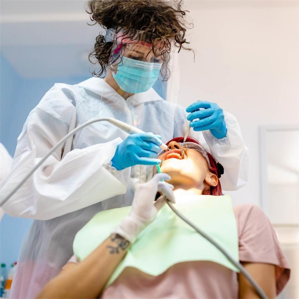 Kadın periodontist, hastanın güzel bir gülümsemeye sahip olabilmesi için minedeki sert ve yumuşak tortuları temizler